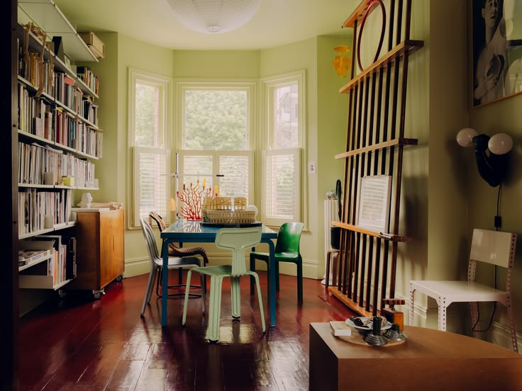 Dining room with a blue table, mismatched chairs, a bay window, built-in bookshelves and a slatted wood screen